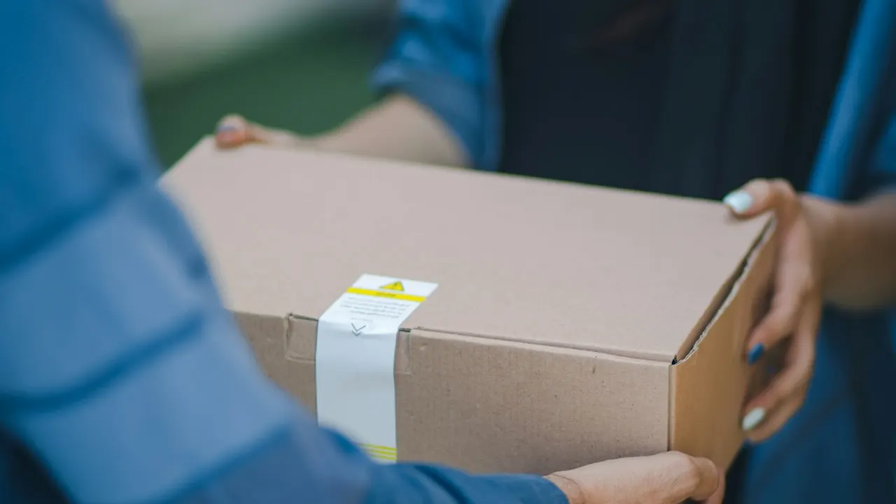 Courier handing a cardboard parcel to a receiver - purchase orders and delivery challans for retail buying